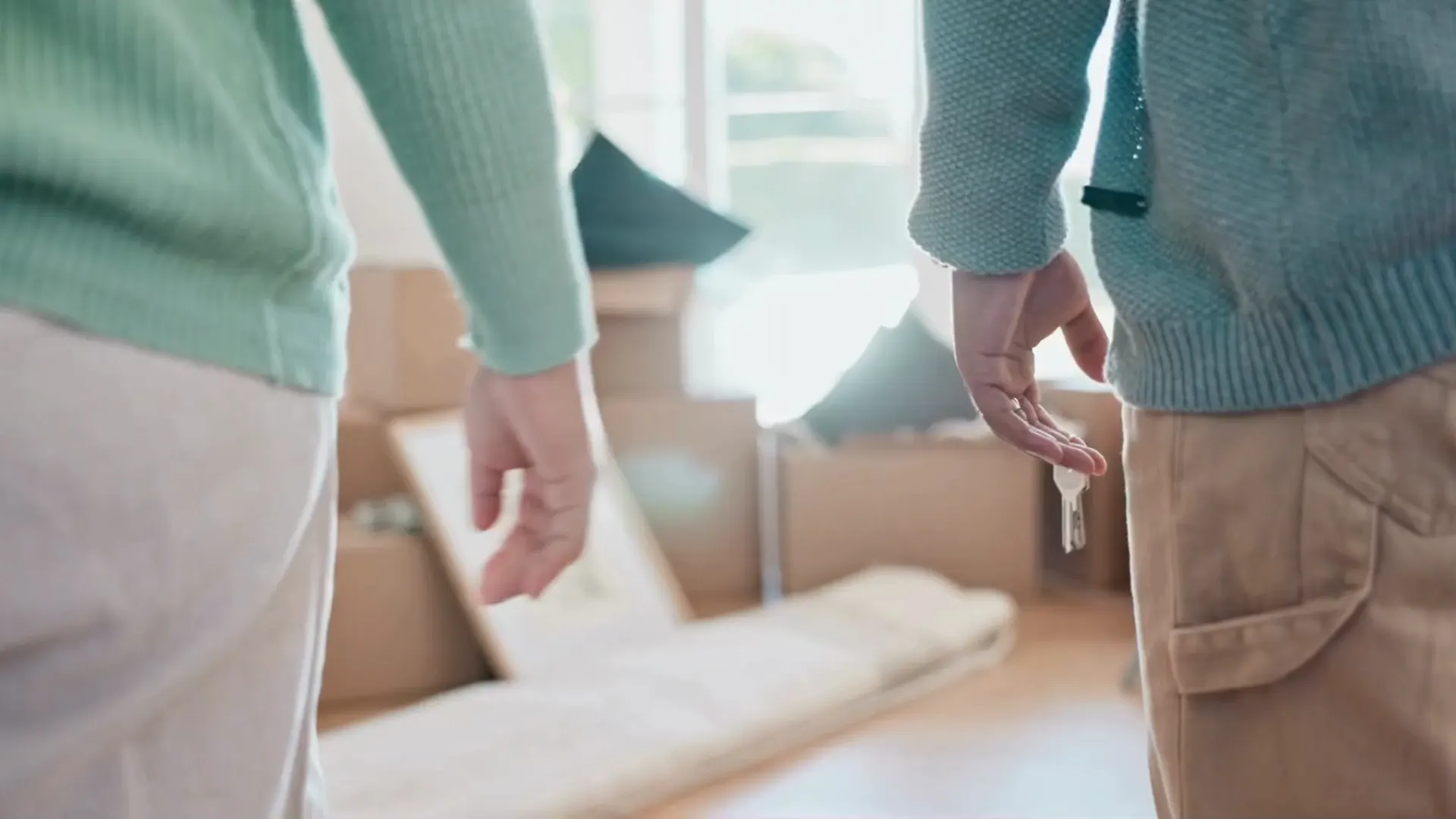 Pareja tomada de la mano con llaves de su nueva casa